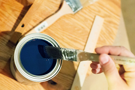 Dipping a trim brush into a quart of BEHR PREMIUM PLUS ULTRA paint