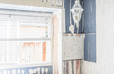 Stripped bedroom wall showing several layers of wallpaper and paint