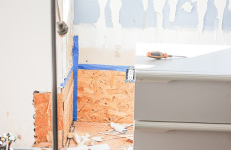 Stripped bedroom wall showing particle board patches and tape