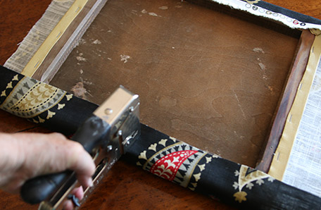 Using a staple gun to attach the new seat fabric