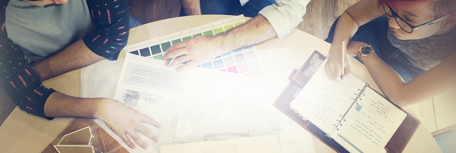 Desk with seated people reviewing a laptop as they choose colors