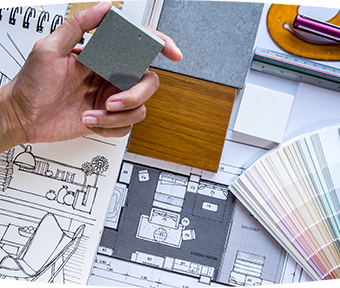 Close-up of hand holding a color tile with interior design sketches in background