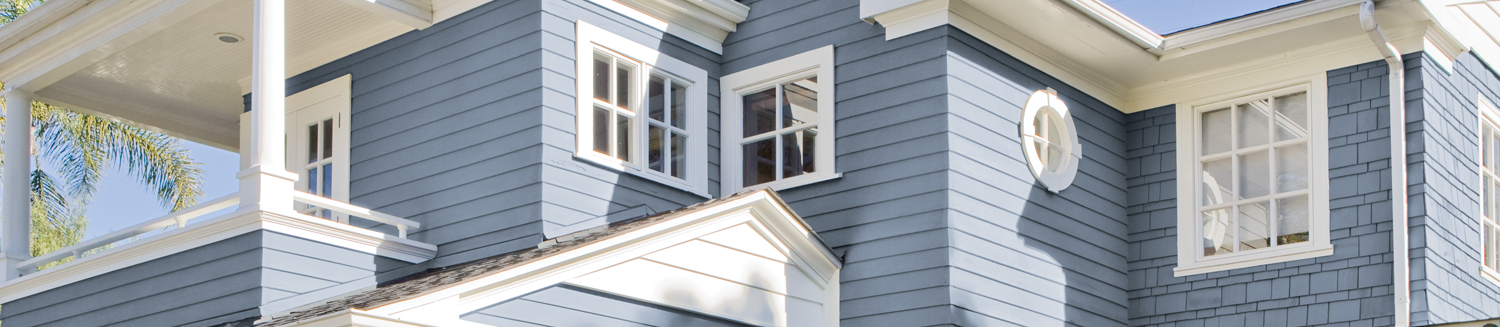 The front side of a blue house with white windows